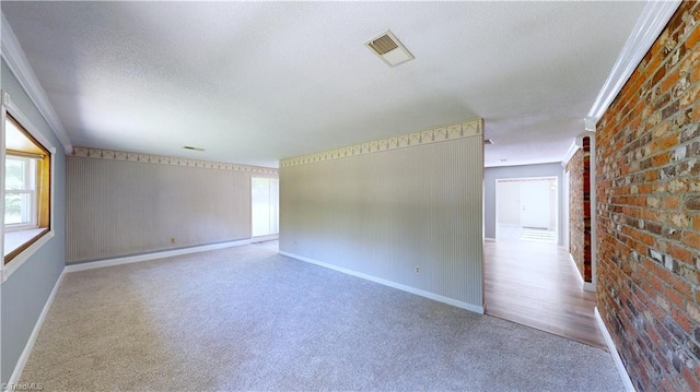 3618 Rockwood Dr, High Point, NC 27265 - empty room featuring brick wall, a textured ceiling, visible vents, carpet floors, and baseboards