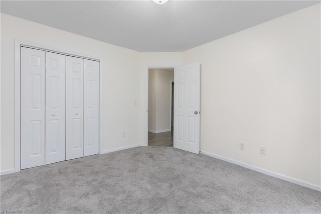 unfurnished bedroom featuring a textured ceiling, light colored carpet, and a closet