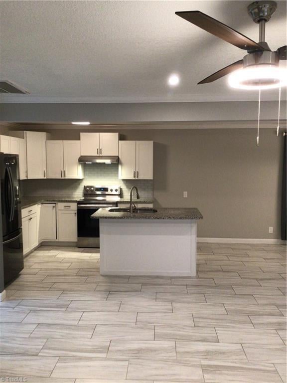 kitchen with visible vents, tasteful backsplash, stainless steel electric range, a sink, and freestanding refrigerator