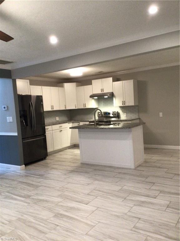 kitchen featuring white cabinetry, an island with sink, dark countertops, and black fridge
