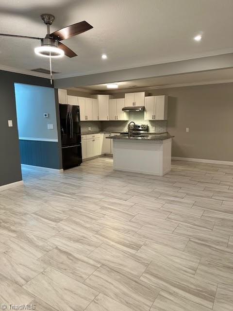 kitchen featuring freestanding refrigerator, open floor plan, dark countertops, and under cabinet range hood