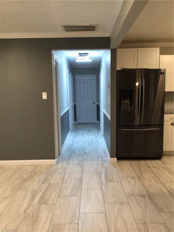 hall featuring baseboards, visible vents, and crown molding