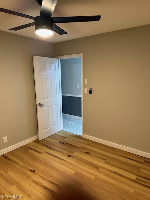 empty room featuring baseboards, light wood-type flooring, and ceiling fan