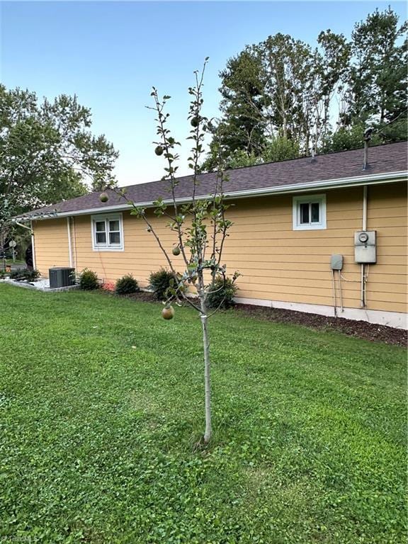 view of side of home with central air condition unit and a lawn