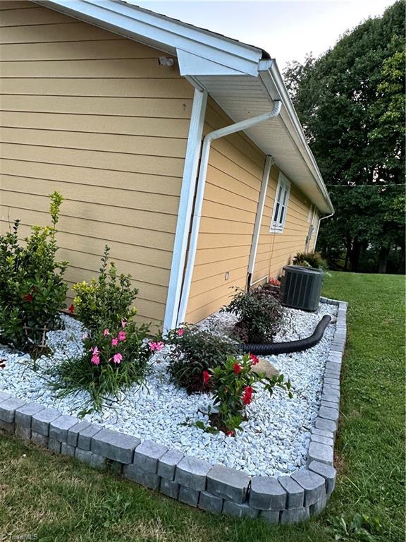 view of side of property with central AC and a yard