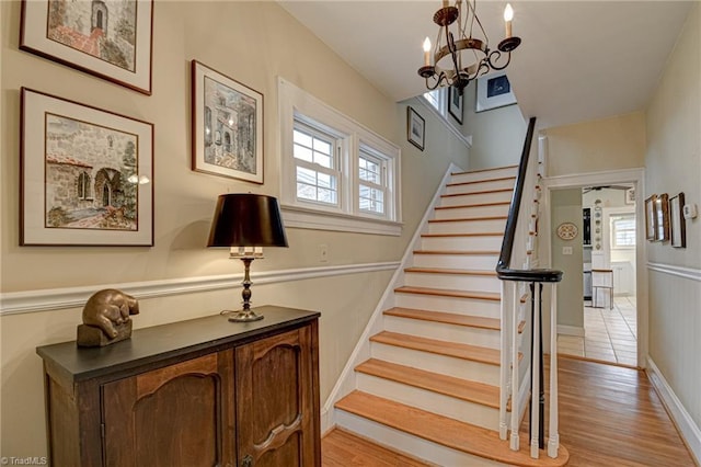 stairway featuring a notable chandelier and wood finished floors