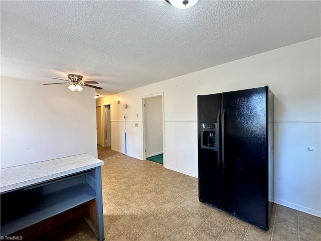 kitchen with a textured ceiling, black refrigerator with ice dispenser, and ceiling fan