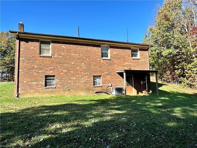 rear view of property with a lawn and central air condition unit