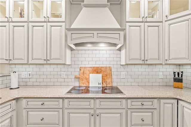 kitchen with premium range hood, white cabinetry, and black electric cooktop