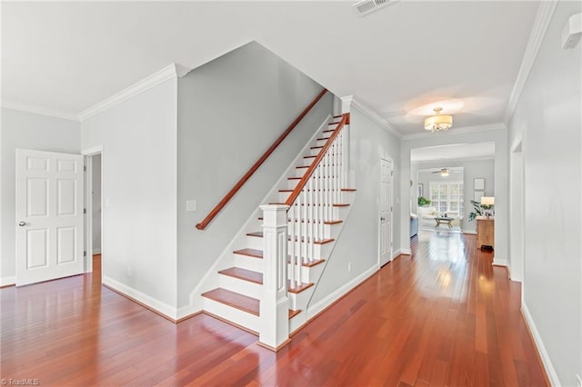 stairway featuring hardwood / wood-style floors, ceiling fan, and crown molding