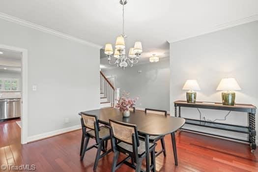 dining space featuring an inviting chandelier, crown molding, and dark wood-type flooring