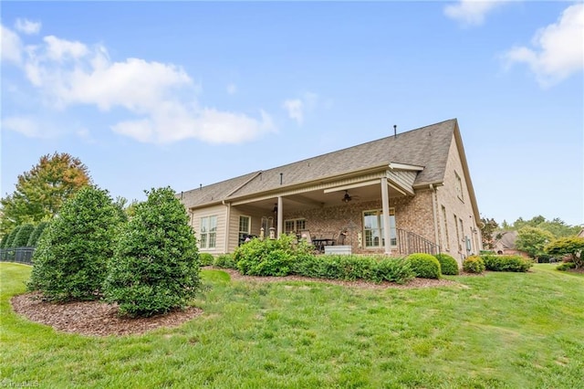 rear view of property with a lawn and ceiling fan