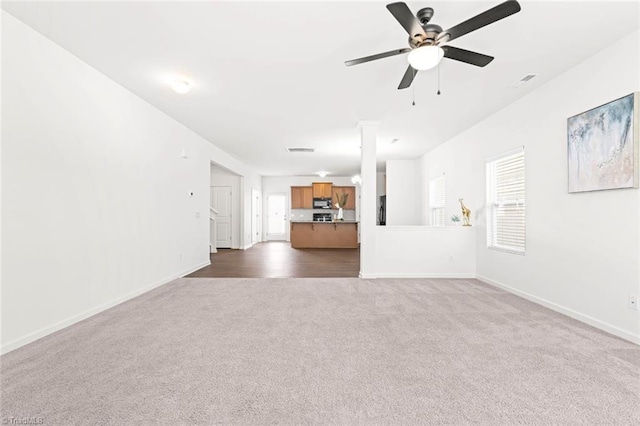 unfurnished living room featuring dark carpet and ceiling fan