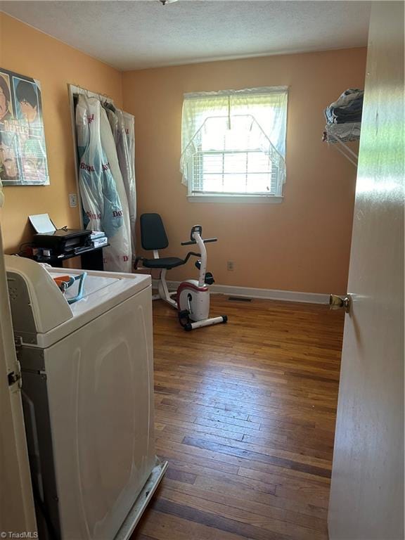 clothes washing area featuring washer / clothes dryer, a textured ceiling, and dark wood-type flooring