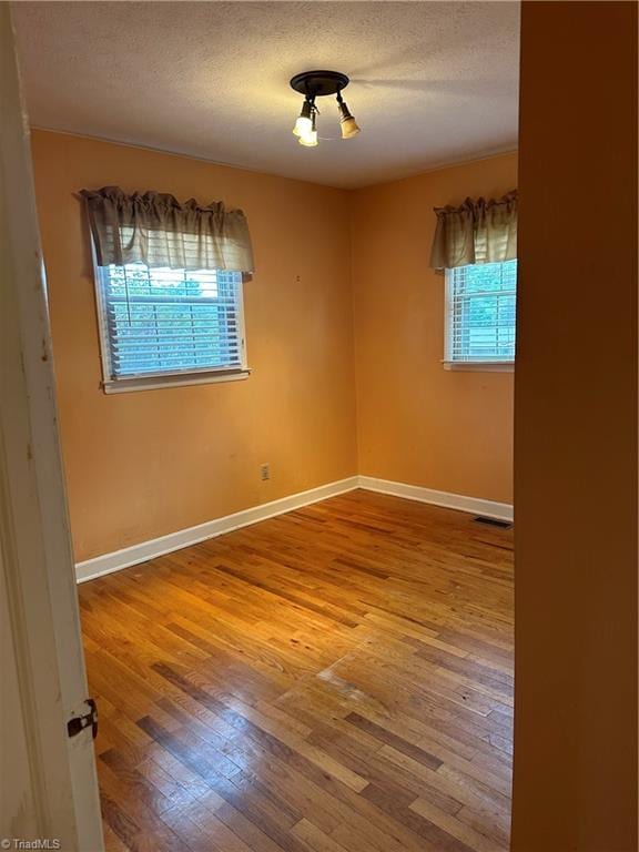 unfurnished room with a textured ceiling and wood-type flooring