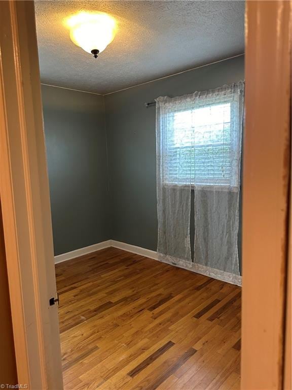 unfurnished room with a textured ceiling and hardwood / wood-style floors