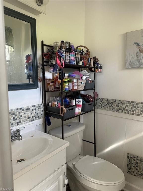 bathroom with vanity, toilet, and decorative backsplash