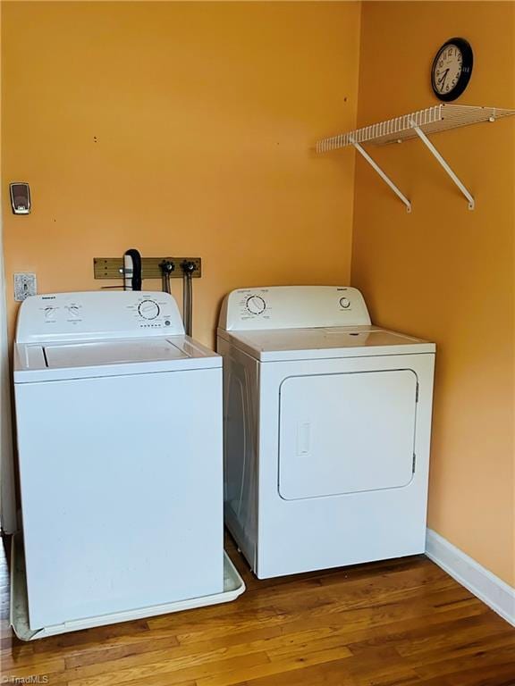 clothes washing area featuring wood-type flooring and washing machine and dryer