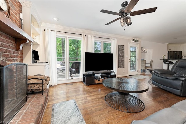 3016 Havasu Way, High Point, NC 27265 - living area featuring light wood finished floors, a ceiling fan, a chandelier, crown molding, and a brick fireplace