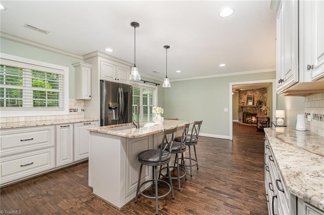 1420 Rankin Rd, Greensboro, NC 27405 - kitchen featuring stainless steel refrigerator with ice dispenser, tasteful backsplash, crown molding, a stone fireplace, and a kitchen bar