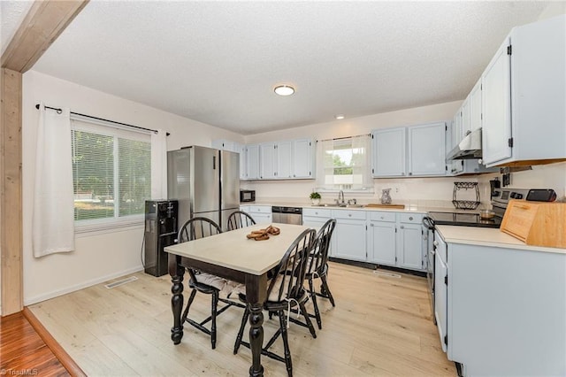 1018 Sequoia Dr, Lewisville, NC 27023 - kitchen featuring under cabinet range hood, light wood finished floors, appliances with stainless steel finishes, a textured ceiling, and light countertops