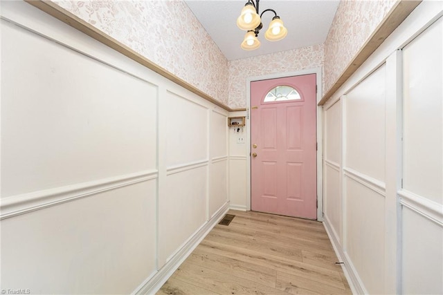 1018 Sequoia Dr, Lewisville, NC 27023 - doorway with wallpapered walls, a decorative wall, light wood-style flooring, and a chandelier