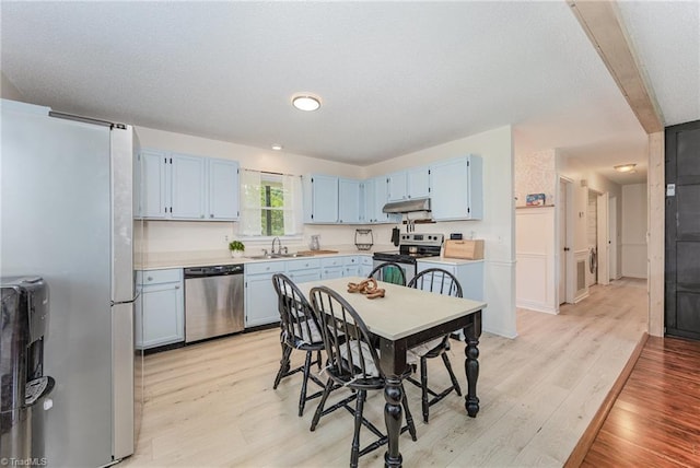 1018 Sequoia Dr, Lewisville, NC 27023 - kitchen with stainless steel appliances, blue cabinetry, light wood-style flooring, under cabinet range hood, and a textured ceiling