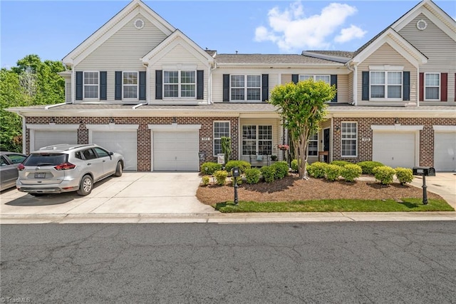 townhome / multi-family property featuring an attached garage, concrete driveway, and brick siding