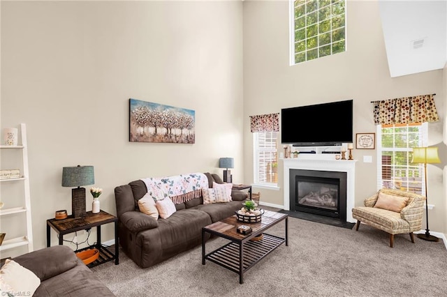 carpeted living room featuring a high ceiling, a fireplace with flush hearth, and baseboards