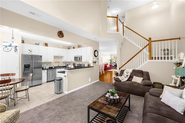 living area featuring stairway, a towering ceiling, light colored carpet, and light tile patterned floors