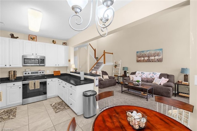 kitchen with appliances with stainless steel finishes, a peninsula, dark countertops, and open floor plan