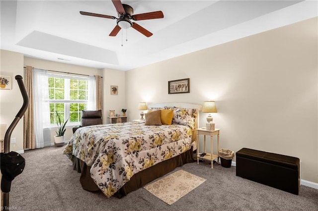 bedroom with carpet, a tray ceiling, baseboards, and ceiling fan
