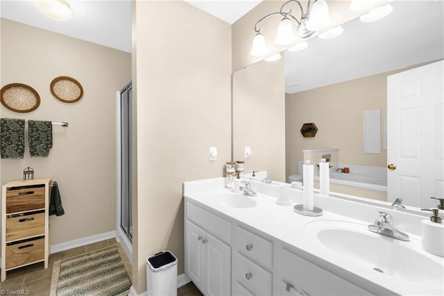 bathroom with double vanity, a stall shower, a bath, and baseboards