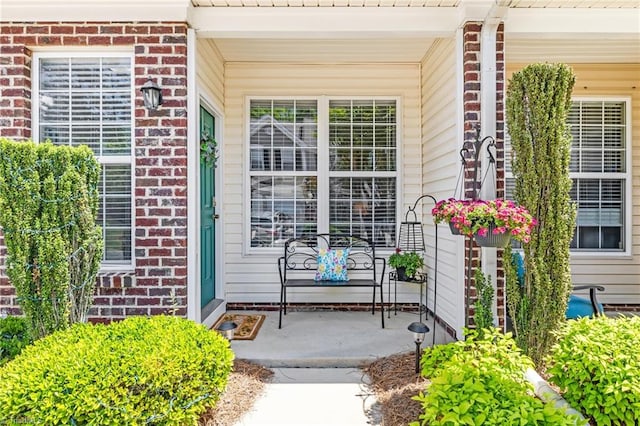 entrance to property with covered porch and brick siding