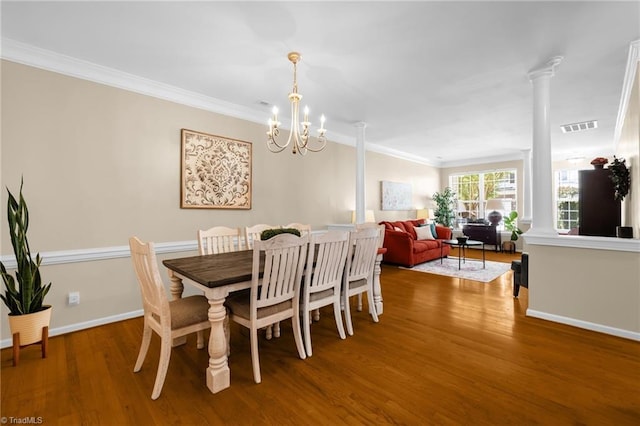 dining room with wood finished floors, a chandelier, ornamental molding, ornate columns, and baseboards