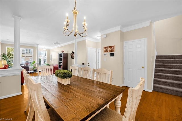 dining space featuring decorative columns, wood finished floors, ornamental molding, stairs, and baseboards