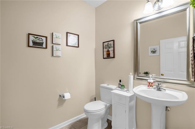 bathroom featuring toilet, tile patterned flooring, baseboards, and a sink