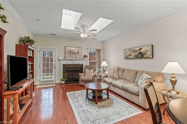 living room with ceiling fan, wood-type flooring, and crown molding