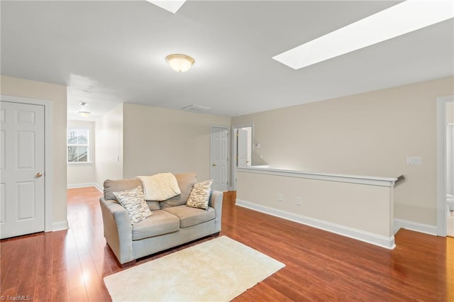 living room featuring hardwood / wood-style flooring and a skylight