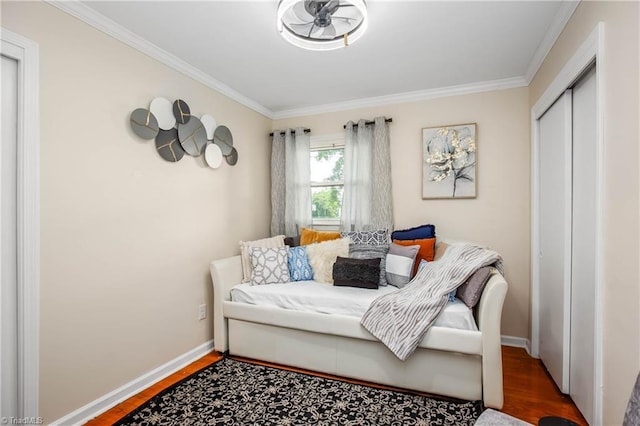 bedroom featuring crown molding, wood finished floors, a closet, and baseboards