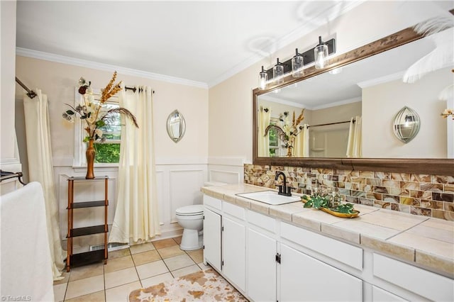 full bath featuring crown molding, tile patterned floors, vanity, toilet, and wainscoting