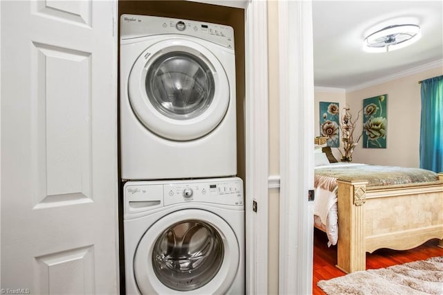 laundry room with stacked washer / dryer, crown molding, and wood finished floors