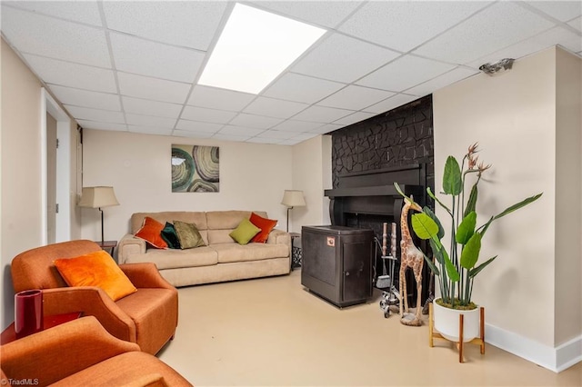 living area featuring a paneled ceiling and baseboards