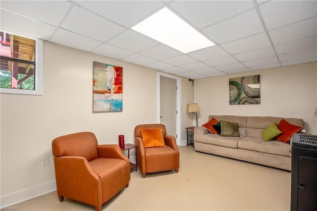 living area with a paneled ceiling and baseboards