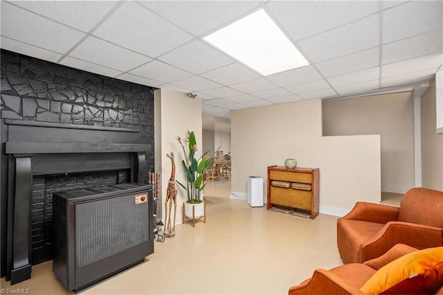 living area featuring a paneled ceiling, concrete floors, and baseboards