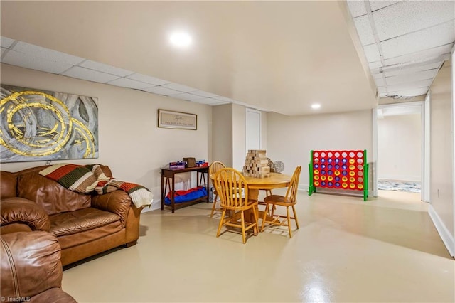 dining space featuring concrete flooring, a drop ceiling, baseboards, and recessed lighting