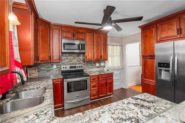 kitchen with appliances with stainless steel finishes, a sink, ornamental molding, ceiling fan, and dark wood-style flooring