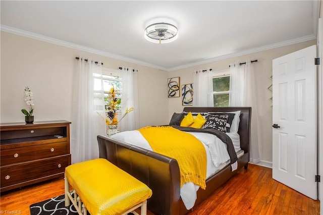 bedroom featuring wood finished floors, multiple windows, and ornamental molding