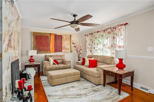 living room with a ceiling fan, wood finished floors, ornamental molding, and baseboards