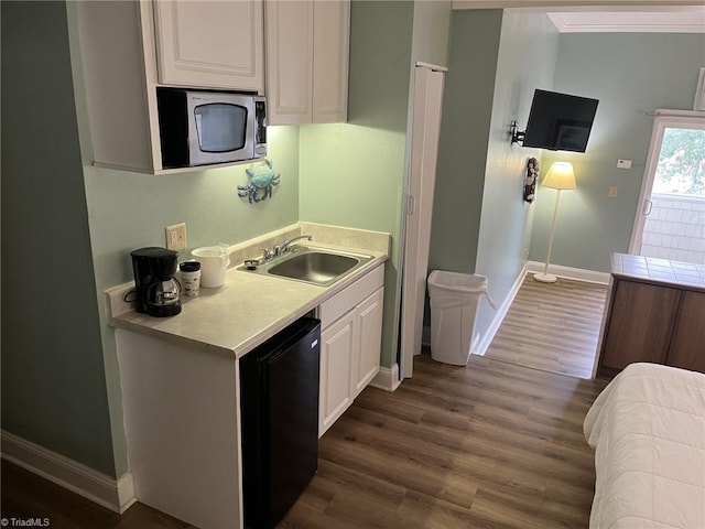 602 Fort Macon Rd, Atlantic Beach, NC 28512 - kitchen featuring a sink, stainless steel microwave, baseboards, dark wood-style flooring, and white cabinets